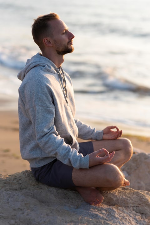 seitenansicht man meditiert am strand